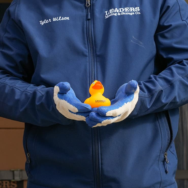 A close up of a Leaders Moving employee holding a yellow rubber duck