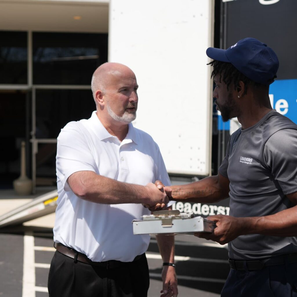 A commercial business owner shakes hands with a Leaders Moving & Storage Co. team member after a successful large delivery