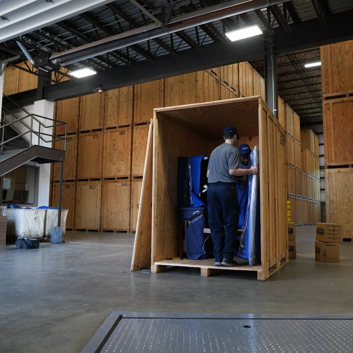 Two Leaders Moving & Storage Co. team members work together to carefully load a crate