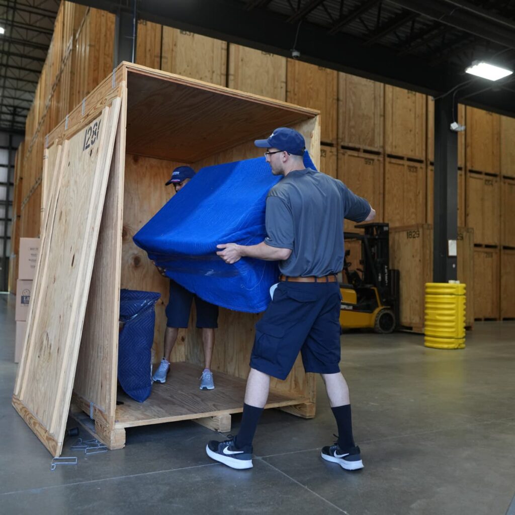Two Leaders Moving & Storage Co. team members work together to professionally load a packed office item into a crate
