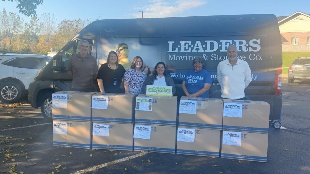 A group of teachers standing in front the Leaders Moving truck with boxes in front of them